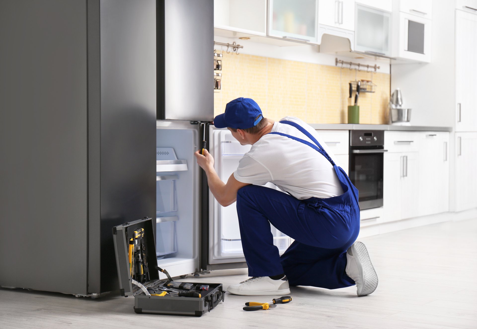 a technician repairing a refrigerator - Expert Appliance Repair Virginia Beach