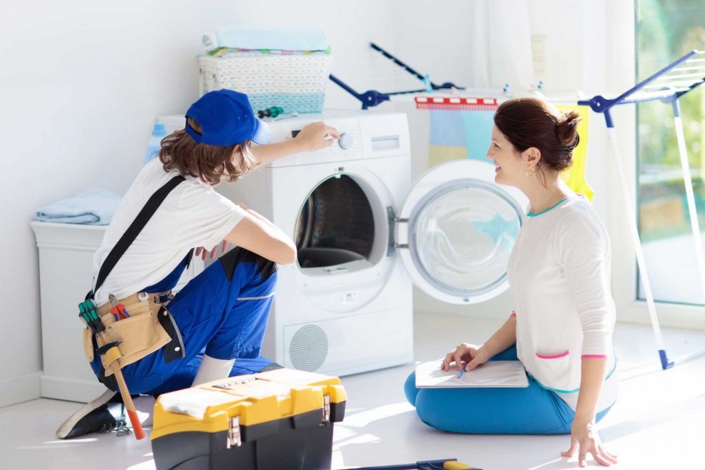 a technician repairing a washer while woman is watching - appliance repair service Virginia