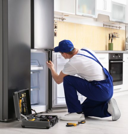 a technician repairing a refrigerator - Expert Appliance Repair Virginia Beach